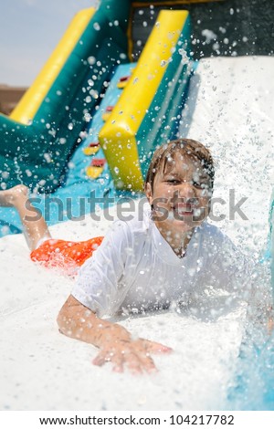 Water Slide Splashdown. Young boy sliding down an inflatable water slide and making a splash.