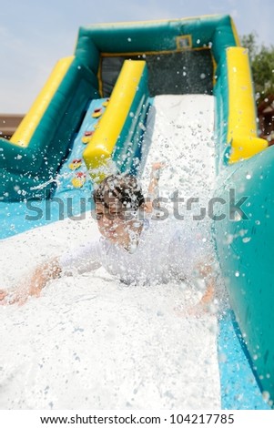 Boy on Water Slide. Boy making a splash as he slides down a water slide.