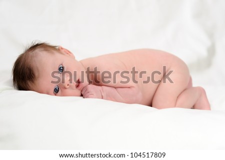 Naked Infant Lying on Stomach with Mouth and Eyes Open. One month old baby boy lying on his front while naked. Shallow DOF.