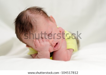 Sleepy Infant Boy. One month old infant with his head in his hands as if he is exhausted. Shallow DOF.