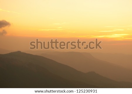 Beautiful sunset at the mountains. Colorful landscape with sun and orange sky