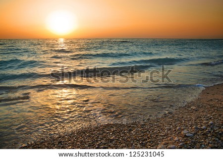 Sunset above the sea. Big sun and waves at beach