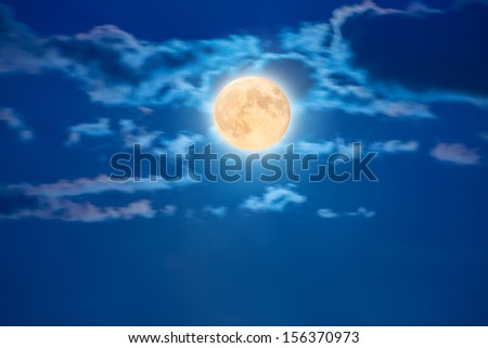 Big shiny moon on the blue sky with clouds