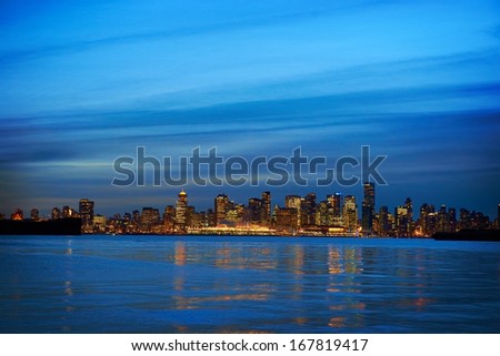 Night city, panoramic scene of downtown reflected in blue water. Vancouver, Canada