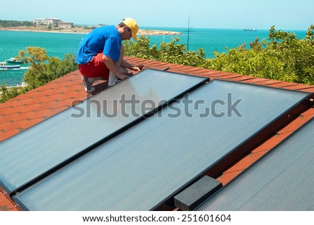 Worker solar water heating panels on the roof.