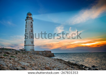 Lighthouse searchlight beam through sea air at night. Seascape at sunset