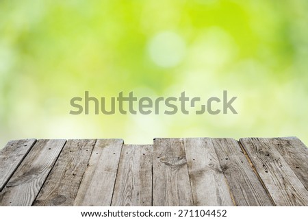 Empty wooden deck table with foliage bokeh background