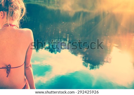 Back view portrait of a beautiful relaxed woman on the beach with blue water background. Instagram filter