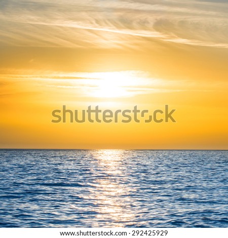 Sunset above the blue sea with sun and orange sky