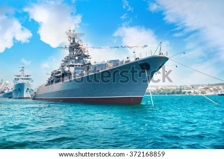 Military navy ship in the bay. Military sea landscape with blue sky and clouds