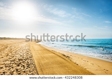 Long coastline, beach with sand and sea at sunset
