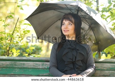 Portrait of beautiful girl with umbrella sitting in the park