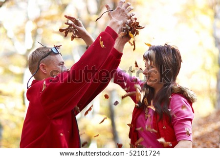 Young couple enjoying the falling leaves in the autumn park