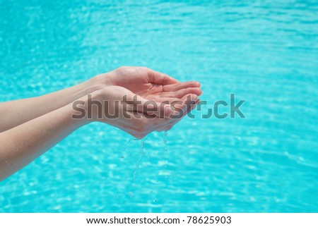 Human hands with clear water on the blue background