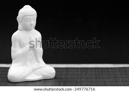 Horizontal black and white shot of a white figure in meditation pose