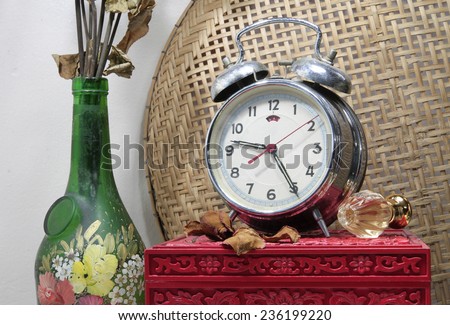 Still life with broken alarm clock, old glass vase with dead rose, classic perfume, vintage box.