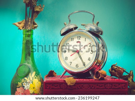 Still life with broken alarm clock, old glass vase with dead rose, vintage box, tone image.