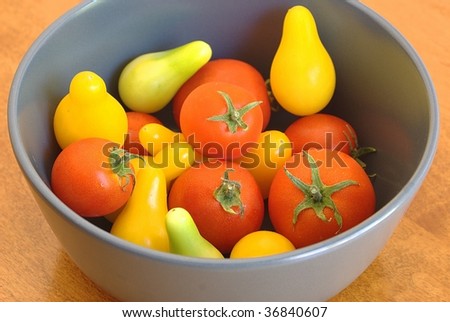 Small red tomatoes with ripe and unripe yellow pear tomatoes in a bowl