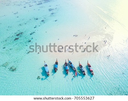 Long tail boats at sand bar beach with crystal clear water of the tropical island in Thailand