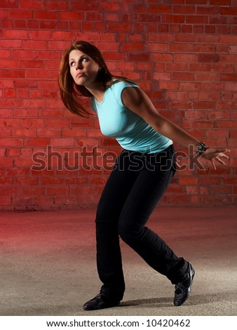 dancing girl at a loss over brick wall