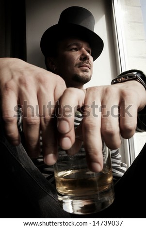 danger man in top hat with glass of whiskey sitting on windowsills