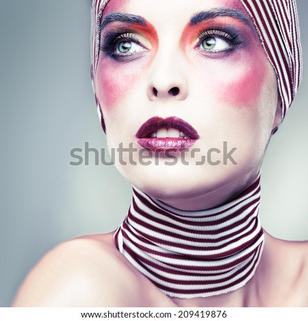 Portrait of girl with a bright theatrical make-up with the striped scarf on a head