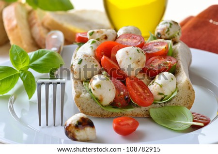 Cherry tomatoes and mozzarella balls with basil filled in an Italian ciabatta bread
