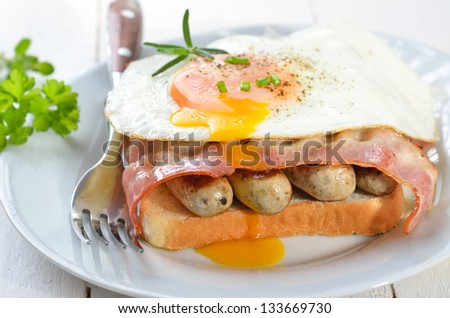 Toast with fried sausages, bacon and egg