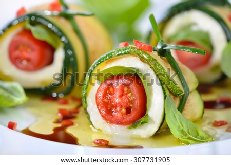 Caprese wrapped with fried zucchini slices, tied and knot with chives, marinated with olive oil and balsamic vinegar