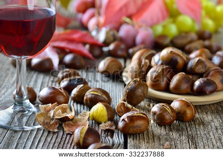 Roasted chestnuts with South Tyrolean red wine on an old wooden table, wine grapes in the background