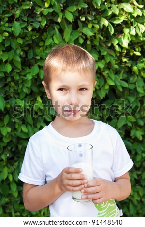 Boy drinking milk from a transparent glass, milk mustache on the face