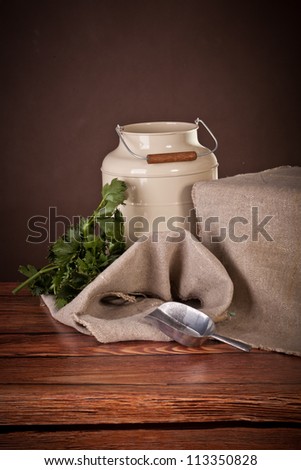 old enameled cans for milk with linen bag on wooden table