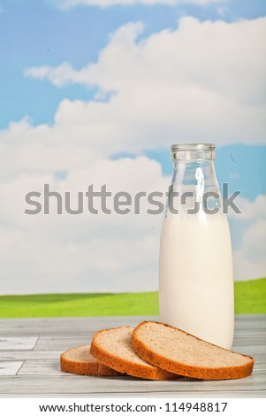 bread and milk in a bottle on a background of the sky - a picnic