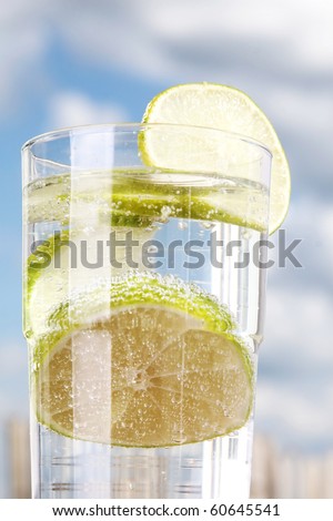 Lime in Soda Water with bubbles in glass against the sky