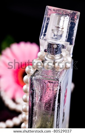 colored glass bottles exclusive perfume on the background of feathers and pearls and flowers with water drops