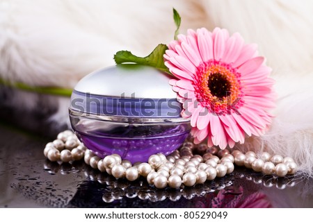 colored glass bottles exclusive perfume on the background of feathers and pearls and flowers with water drops