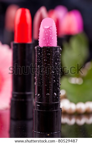 lipstick and nail polish on a background of roses, flowers, pearls and drops of water