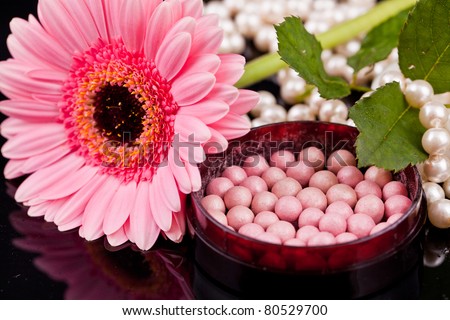 Bronzing pearls in powder box with a brush, on the background of the flowers, pearls, drops of water.