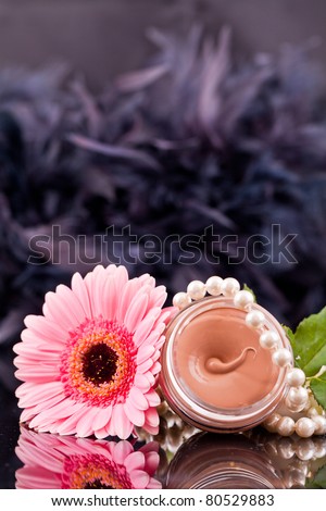 Beige liquid in the round glasses box with pearls,flowers and dropes water.