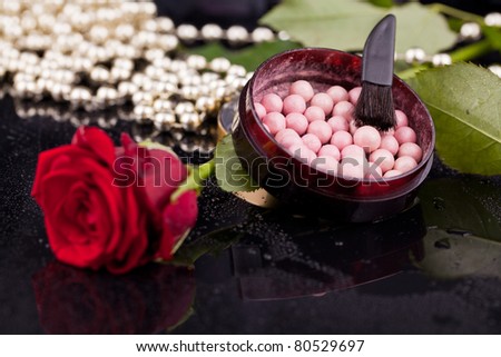 Bronzing pearls in powder box with a brush, on the background of the flowers, pearls, drops of water.