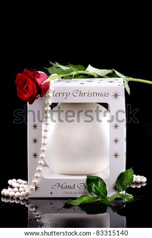 Christmas bauble pearl in the composition of pearls and a rose on a black background