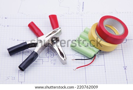 Electric clamps and battery on a background of the electric scheme