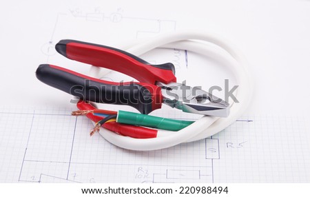 Pliers and electric cable on the background of the electric scheme
