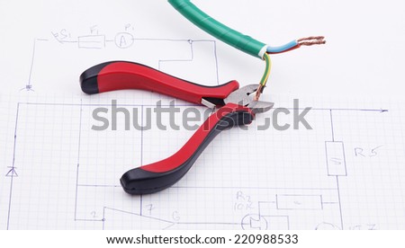 Metal nippers and electric cable on the background of the electric scheme