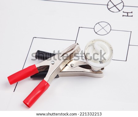 Energy saving fluorescent light bulb and electric clamps on on a background of the electric scheme