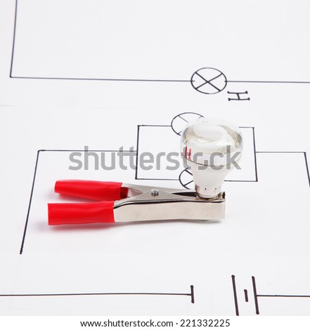 Energy saving fluorescent light bulb and electric clamps on on a background of the electric scheme