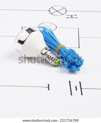 Energy saving fluorescent light bulb  and plastic ties on a background of the electric scheme
