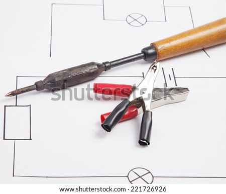 Electric clamps and a soldering iron on a background of the electric scheme