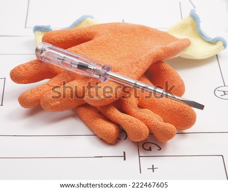 mounting gloves and electric screwdriver on a background of the electric scheme
