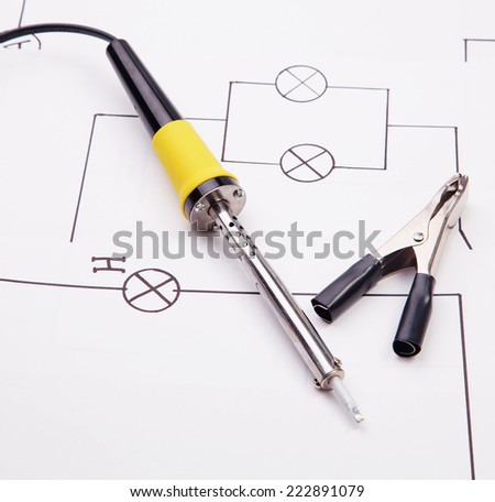 Soldering iron and Electric clamps on a background of the electric scheme
